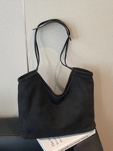 Minimalist large black tote bag in matte finish shown in a clean indoor setting