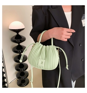 Détail d'un sac à main plissé vert clair avec boucle magnétique et poignée fine