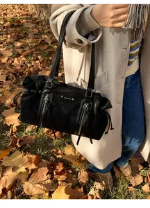 Outdoor shot of a black suede tote bag featuring side tassels and dual zipper details