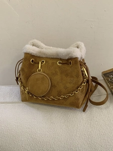 Retro brown hobo bucket bag with faux fur trim and embossed pattern on a beige sofa