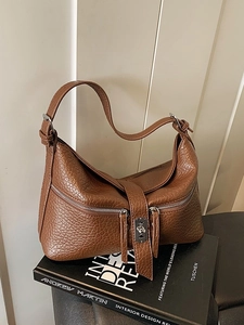 Brown lychee leather shoulder bag with silver zippers and blade metal buckle on books