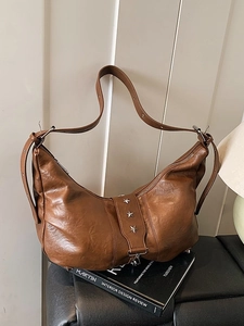 Vintage brown leather crescent tote bag featuring star metal rivets and adjustable strap