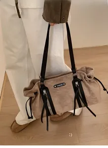 Detail of light brown suede tote bag with black leather straps and zipper accents