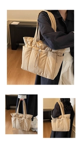 Detail of beige quilted puffer tote bag featuring side drawstring pockets and wide straps