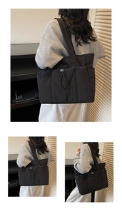Macro detail of black puffy nylon tote bag featuring front drawstring pocket and padded strap