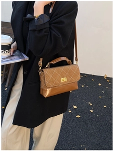 Detail of a brown quilted crossbody bag with a gold twist lock on a street style model