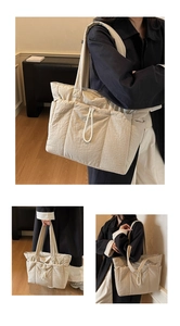 Detail view of large beige quilted nylon tote bag with drawstring buckle and padded texture