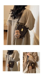 Detail of vintage brown bucket bag featuring gold metal clasp and cute plush bear charm