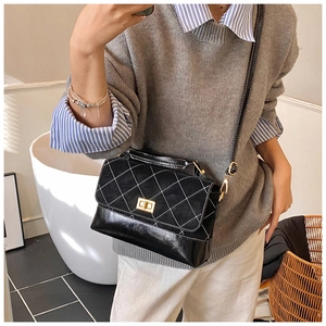 Detail of black quilted crossbody bag with frosted leather and gold metal buckle
