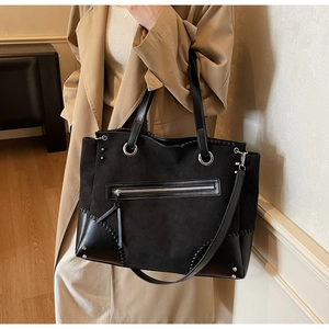 Dettaglio della borsa tote patchwork nera con anelli argentati e cuciture a contrasto
