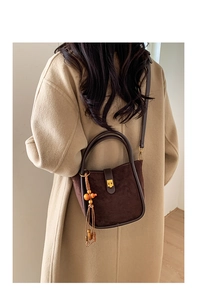 Détail du sac seau en daim marron avec fermoir doré vintage et breloque à glands