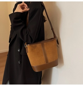 Detail of vintage brown suede and leather bucket bag worn by model on shoulder