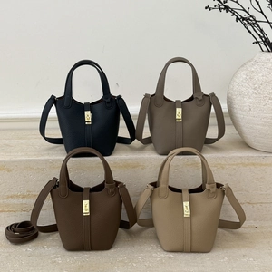 Detail of four bucket bags in litchi grain leather with gold locks on stone steps