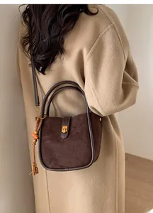 Sac seau en daim marron avec pompon décoratif et boucle en métal style bambou