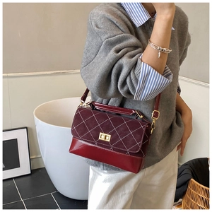 Detail of burgundy quilted shoulder bag featuring gold twist lock and smooth leather texture