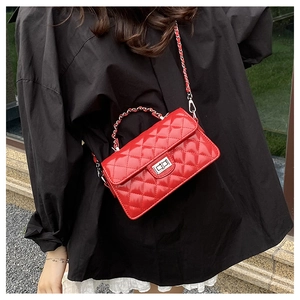Détail d'un sac bandoulière rouge matelassé avec fermoir métal et bandoulière chaîne