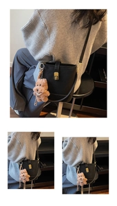 Detail of black leather bucket bag with gold lock and brown plush bear charm accessory