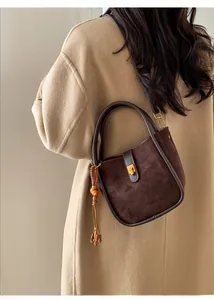 Vue détaillée du sac en cuir mat marron foncé avec boucle dorée et gland en bois