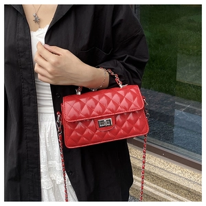 Détail du sac bandoulière rouge matelassé avec fermoir argenté porté par un mannequin
