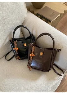 Vue détaillée des sacs seaux vintage en daim avec glands en perles de bois sur canapé