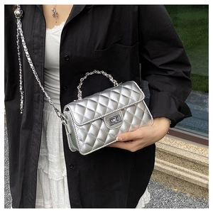 Gros plan sur le sac argenté matelassé avec texture métallique et serrure rotative