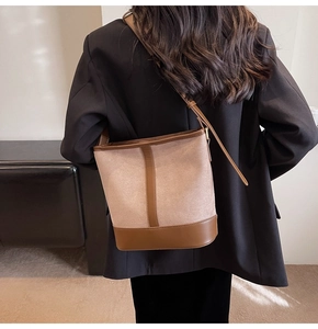 Model view of beige and brown bucket bag worn over a black blazer for a chic casual style