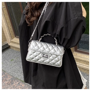 Détail du sac matelassé argenté avec fermoir métallique et bandoulière chaîne