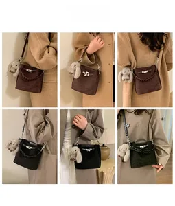 Detail view of suede bucket bag with metal turn-lock and woven handle in two colors