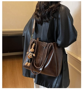 Close-up of brown leather tote bag with woven shoulder strap and cute bunny charm