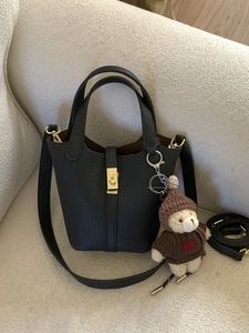 Classic black leather bucket bag with gold hardware and a cute teddy bear charm