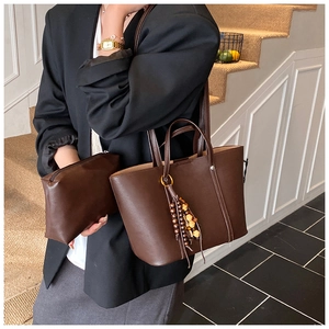 Detail of dark brown tote bag with zipper pouch and vintage wooden bead tassel accessory