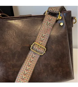 Close-up of vintage brown tote with colorful woven wide strap and brass hardware details