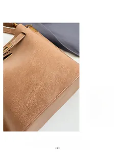 Detailed close-up of textured brown leather bag with golden hardware and fine stitching