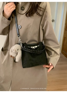 Detailed view of black suede bucket bag featuring silver twist lock and plush rabbit charm
