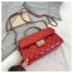 Détail du sac matelassé rouge avec fermoir rotatif argenté et bandoulière sur denim