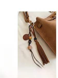Detail view of brown suede bucket bag with gold lock and stylish tassel charm decoration
