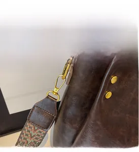 Detail of dark brown leather tote with vintage texture and gold metal hook attachment