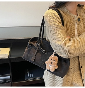 Detail of dark brown suede tote bag with metal buckle and cute plush puppy charm