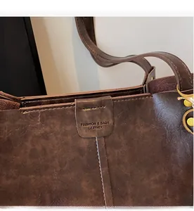 Detailed macro view of the dark brown leather texture and stitching on a vintage tote bag