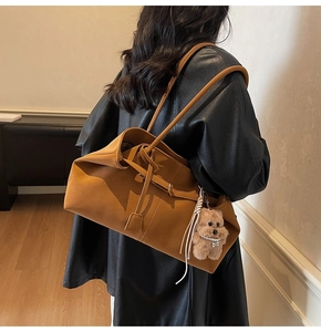 Brown leather tote bag featuring a cute teddy bear charm and tassel detail