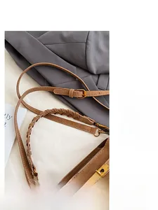 Detail of brown leather bucket bag featuring gold twist lock and woven shoulder strap