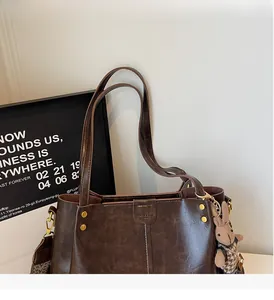 Detail of dark brown tote bag featuring retro texture, rivets, and a patterned strap