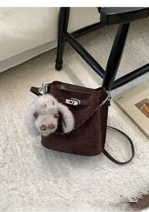 Detailed shot of retro brown suede bucket bag with metal turn-lock and plush bunny charm