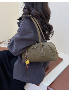 Detail of olive green Boston bag featuring lychee texture and floral pendant charm