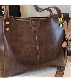 Detail of vintage brown leather tote bag with ethnic strap and plush rabbit charm