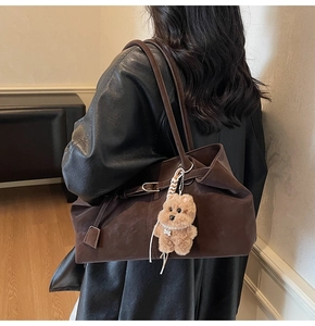 Detail of soft brown suede tote bag featuring a cute teddy bear charm and large capacity