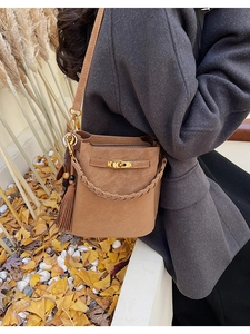 Detail view of a vintage brown bucket bag with tassel and gold-tone turn-lock buckle