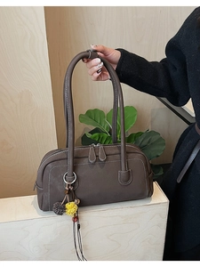 Detail of a dark brown pebble leather Boston bag with floral charm and silver hardware