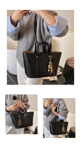 Close-up of minimalist black tote bag with vintage wood bead tassel detail