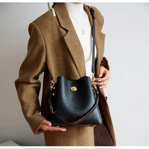 Detail of black lychee leather bucket bag with gold turn-lock and adjustable strap
